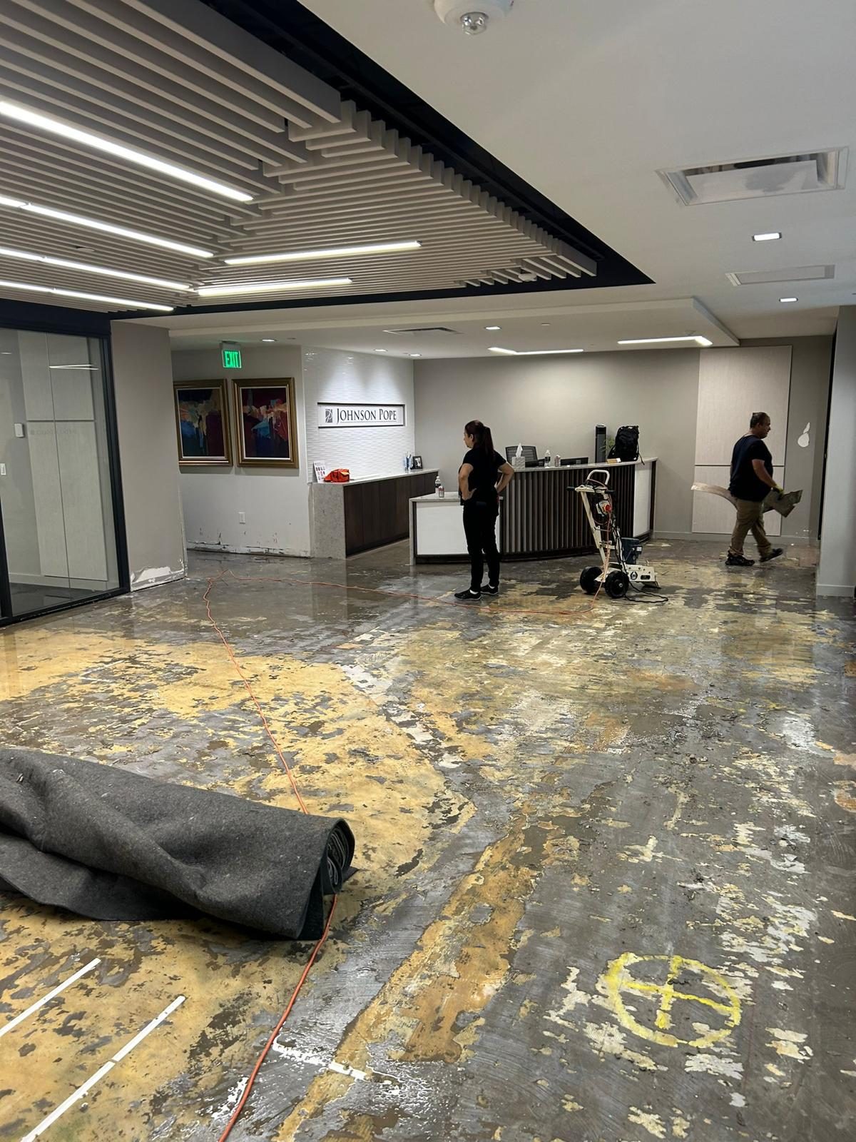 Law firm lobby with carpet peeled back and the slab being scraped by the crew