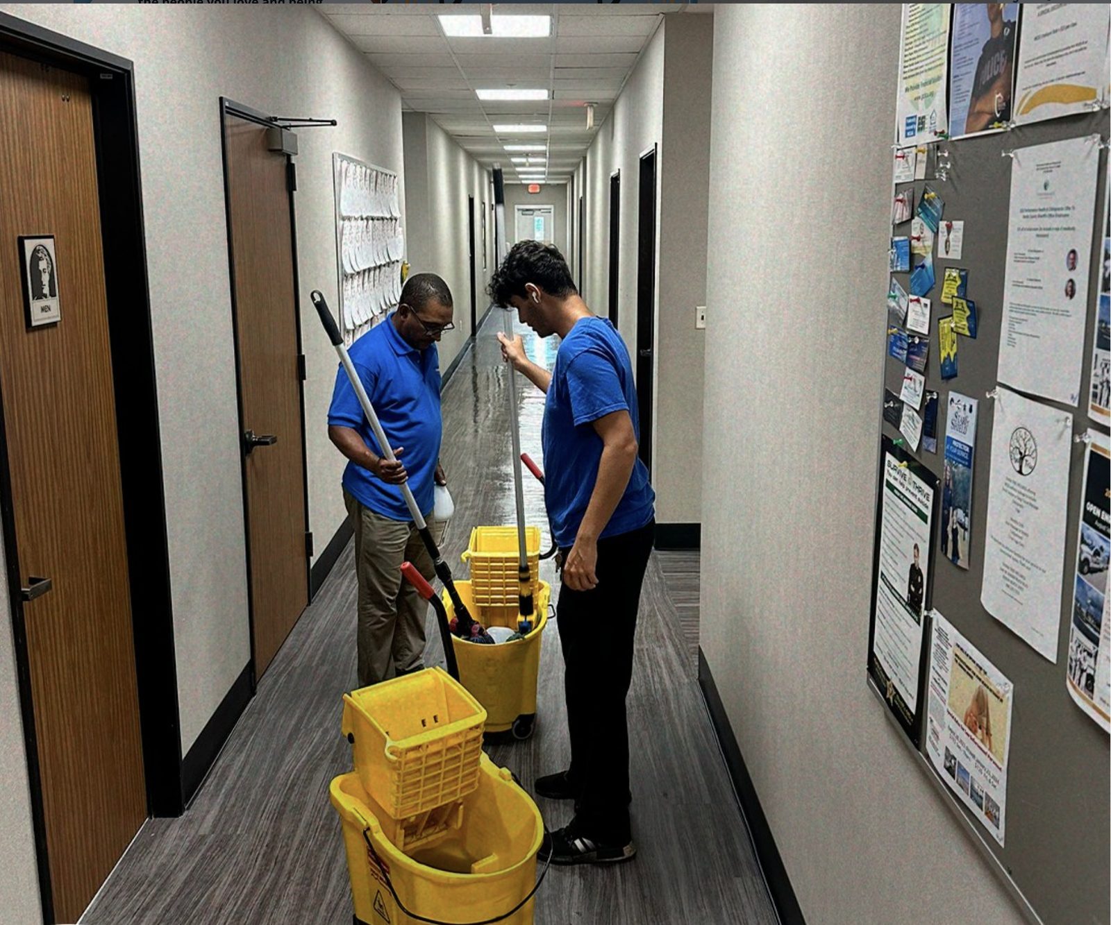 Two BlueSky cleaners mopping an office corridor with dual yellow wringer buckets