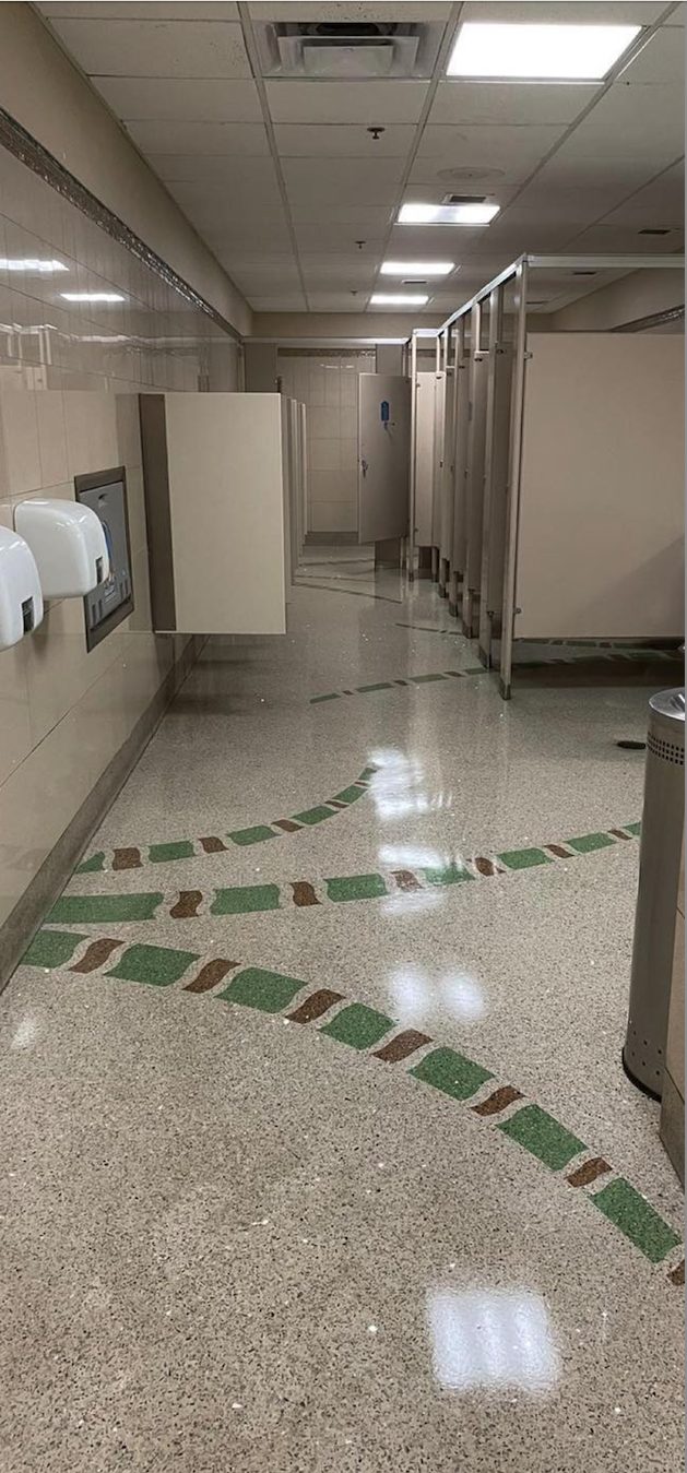 Same airport restroom terrazzo burnished to a mirror shine reflecting the overhead lights