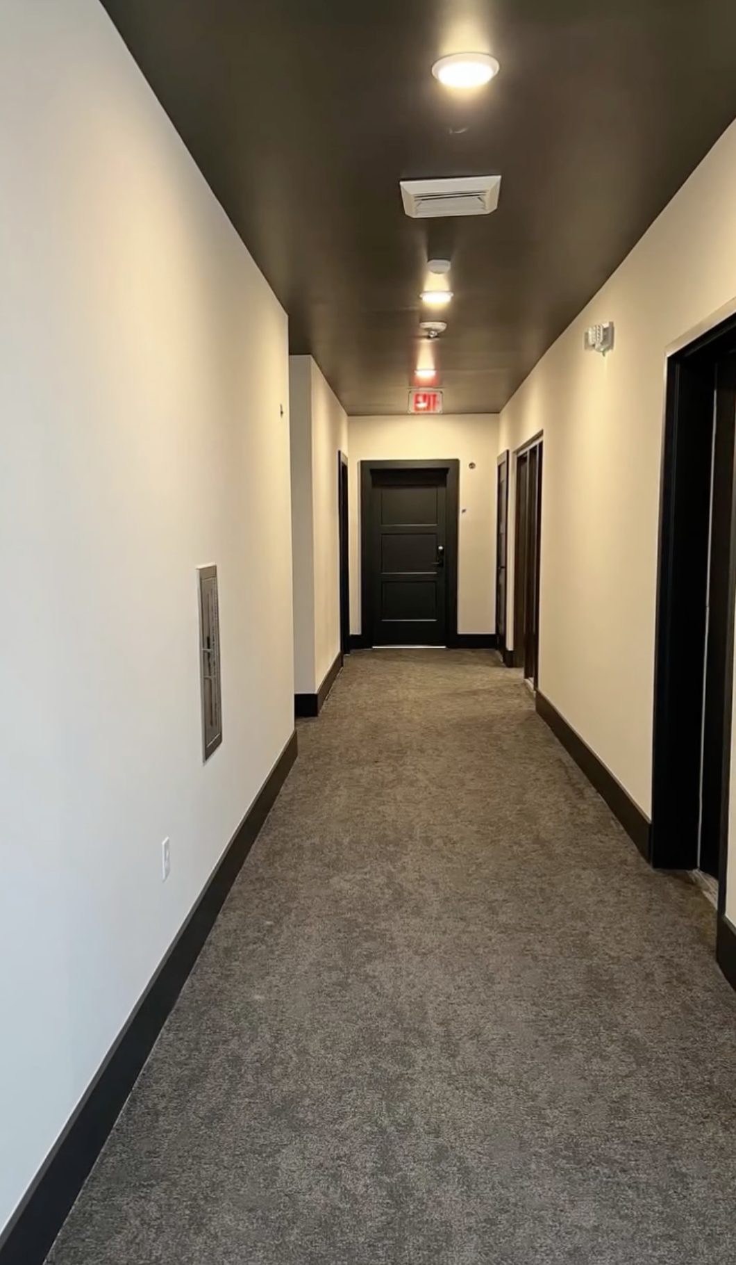 Same corridor turned over with clean carpet, finished trim and lit fixtures