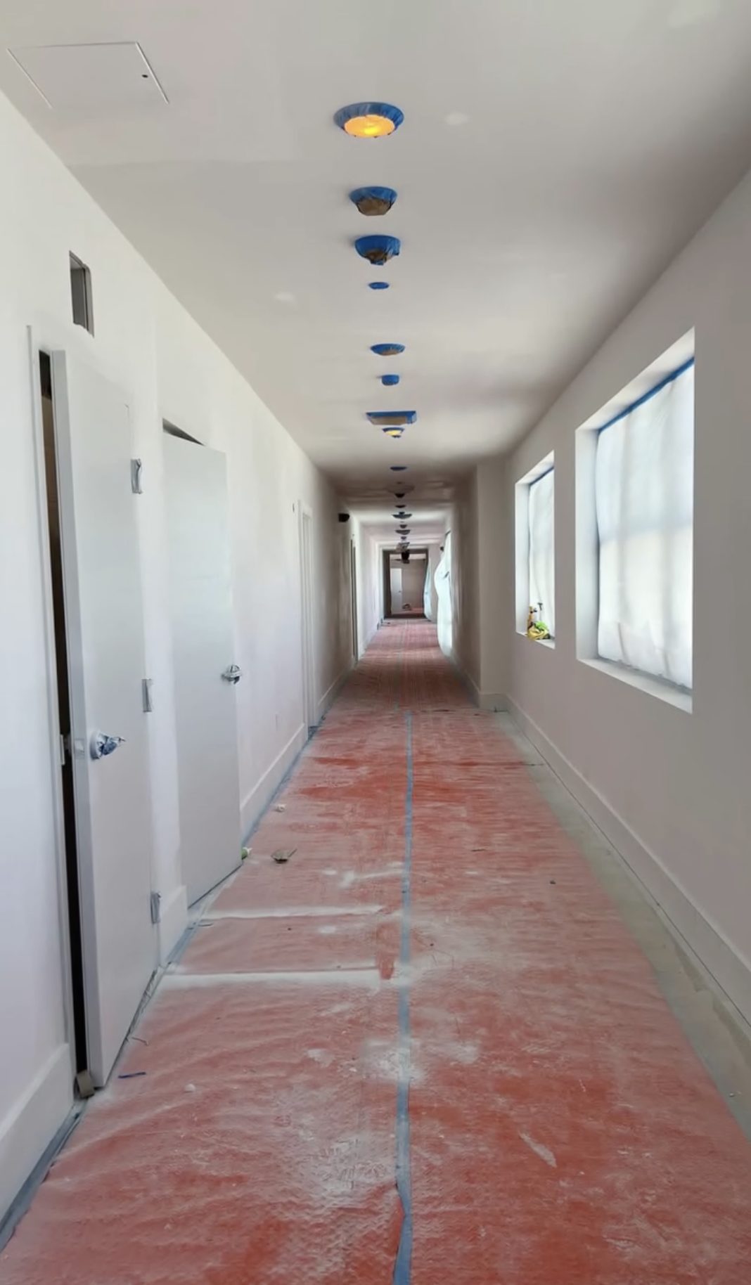 Corridor floor under red rosin paper, windows masked and door hardware taped for finishing