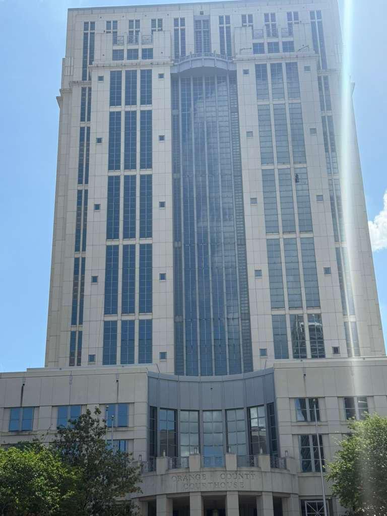 Full Orange County Courthouse tower elevation with a technician suspended mid-facade